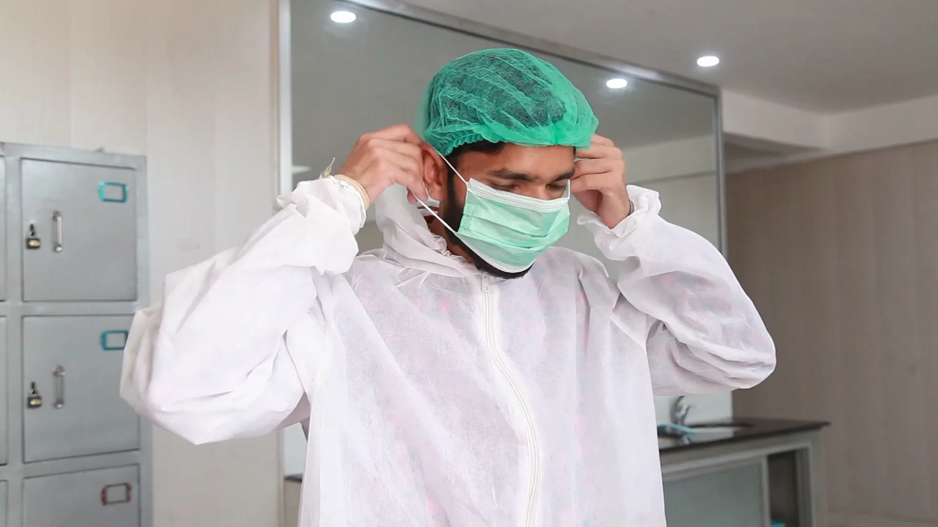 A production worker fitting his face mask in the changing room before a shift.