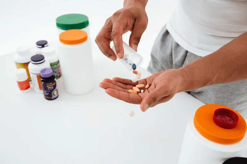 A man shaking supplement tablets from a bottle into his hand.