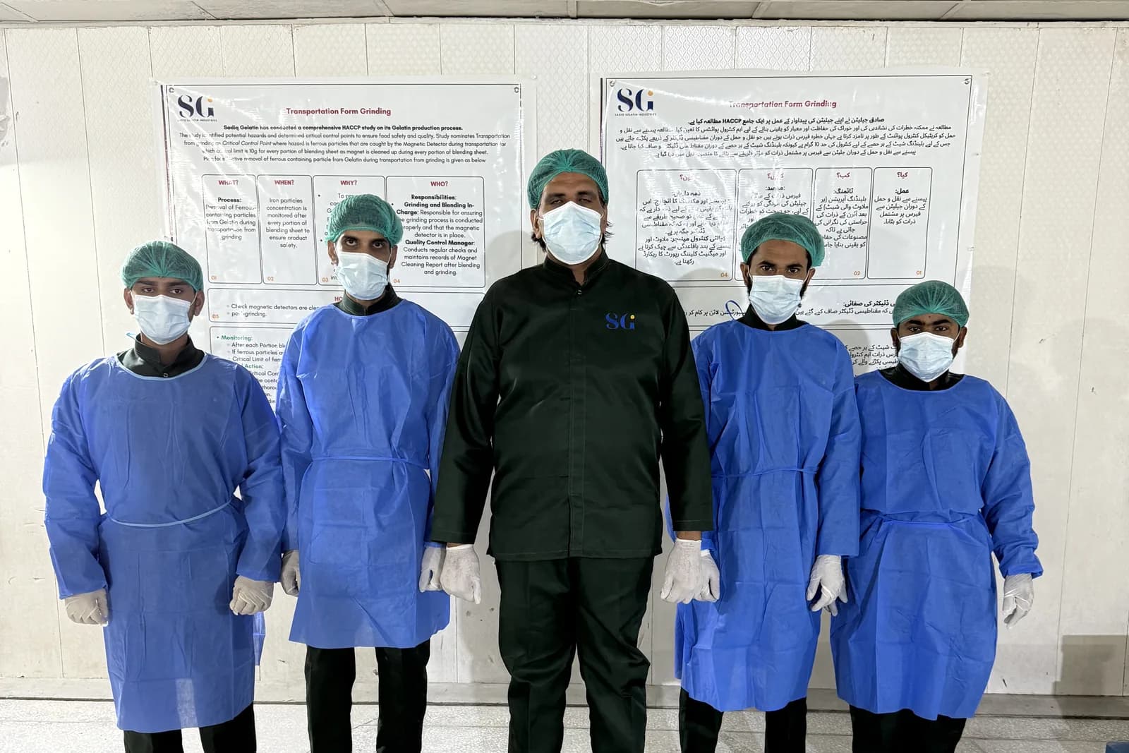 Sadiq Gelatin production staff in blue hygiene gowns, overshoes and hairnets with their supervisor, beneath the plant's posted hygiene procedures.