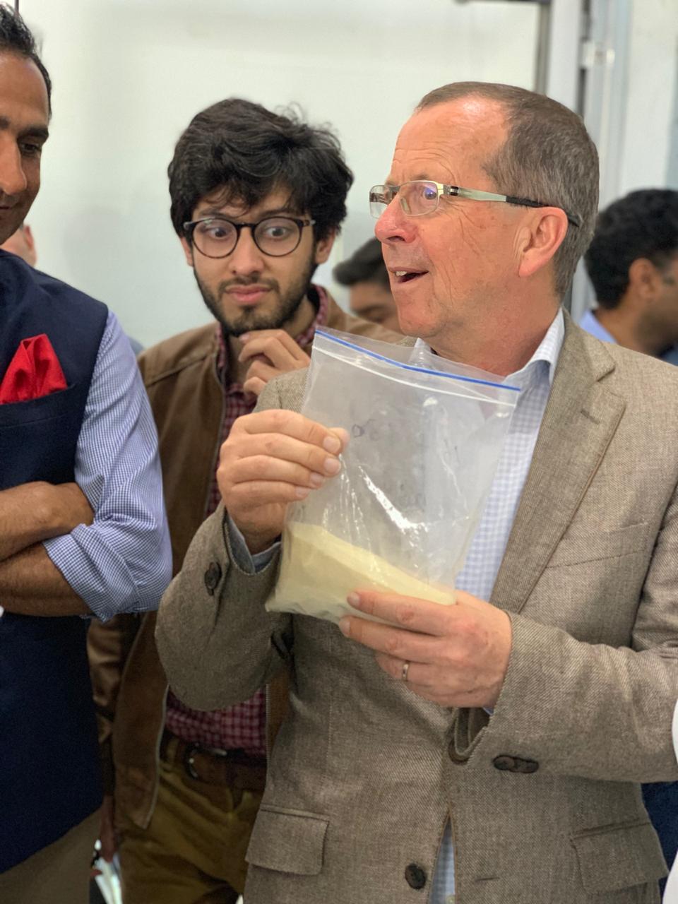 Ambassador Martin Kobler holding a sealed sample of finished gelatin powder during the facility tour.