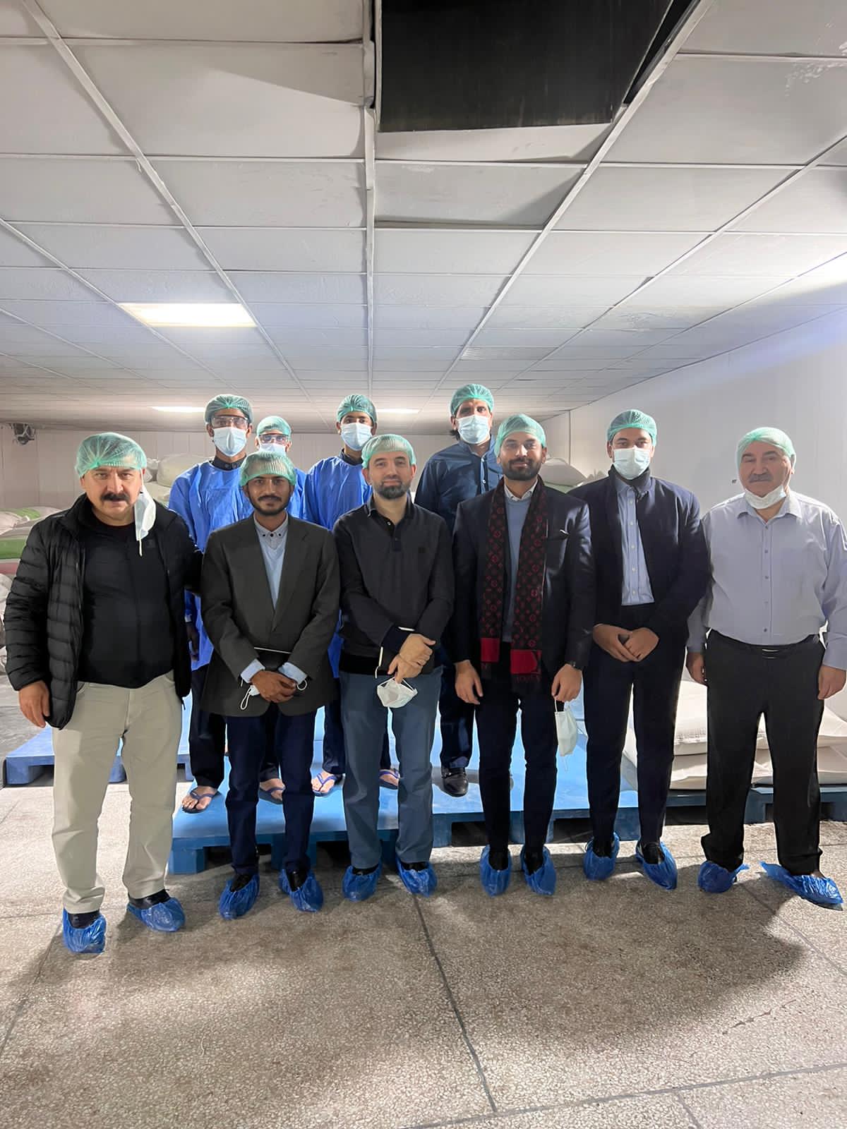 The TSE delegation and Sadiq Gelatin staff in hygiene caps and shoe covers inside the facility.